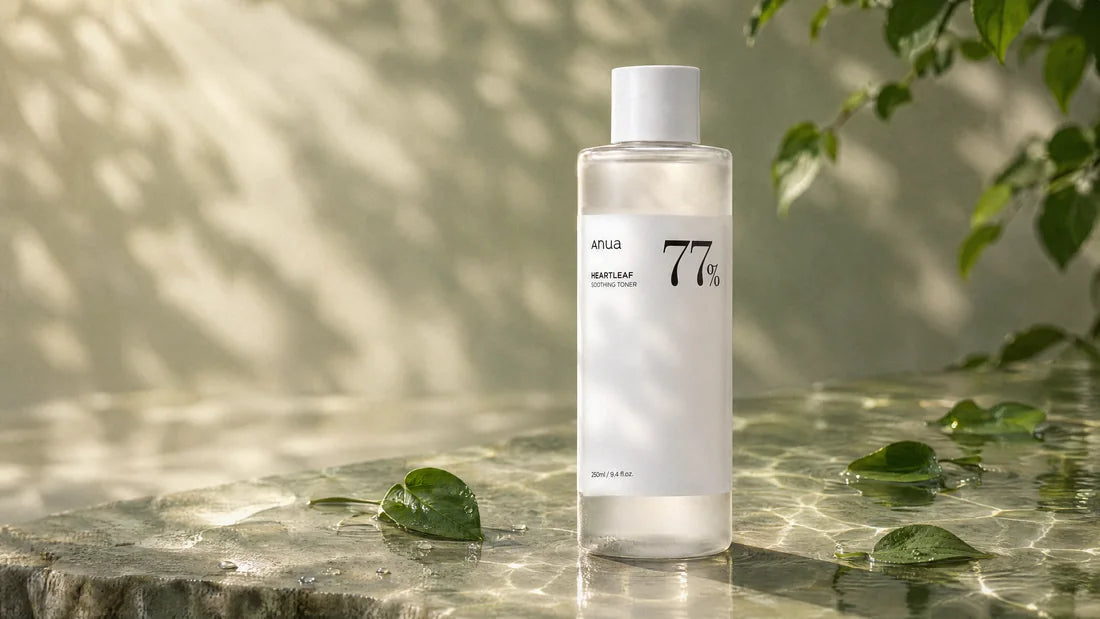 Anua Heartleaf 77% Toner standing in shallow water on pale stone with heartleaf leaves, in dappled morning sun